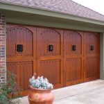 Premium Finish Wood Garage Door with Speakeasy Grills over Windows and Decorative Clavos